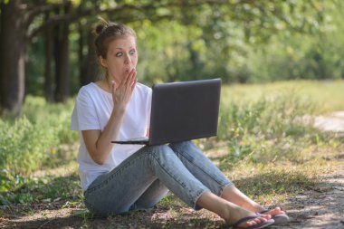 Belgili tanımlık laptop ile kız parkta şaşırır