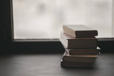 Bir pencerede birkaç kitap yığını