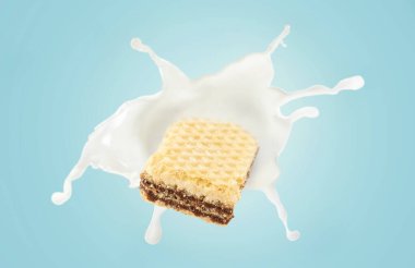 Mavi arka planda süt sıçraması olan waffle.