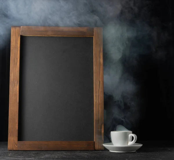 A cup of hot coffee and a chalk board