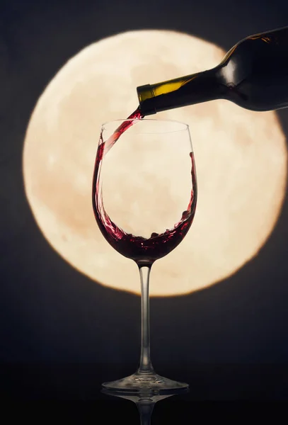 Pouring red wine against the background of the moon