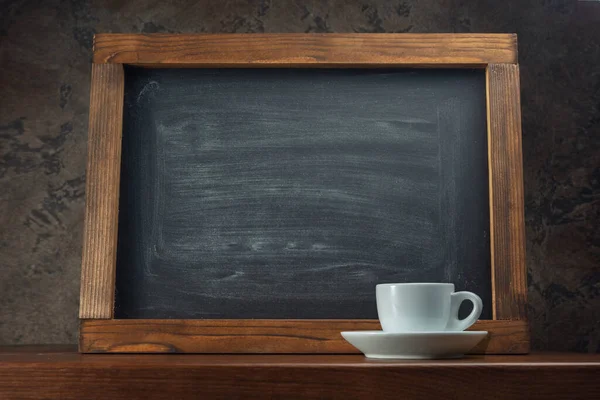 Chalk board on the table and a cup of coffee