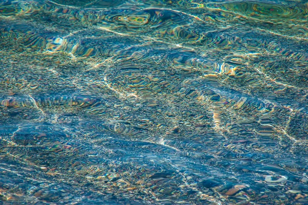 Fond de pierres dans l'eau cristalline bleue — Photo