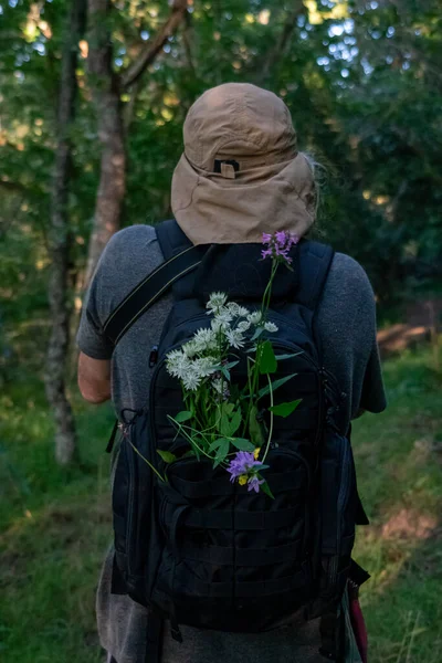 头戴帽子 背着装满鲜花的背包的男人 — 图库照片