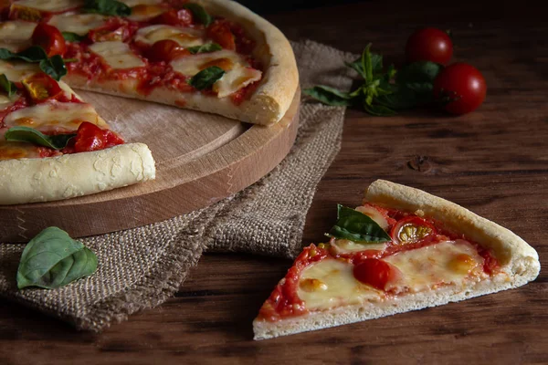 Margarita pizza em uma mesa de madeira com uma peça separada — Fotografia de Stock