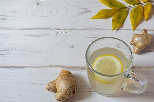 Ginger tea with lemon and leaves on a white table