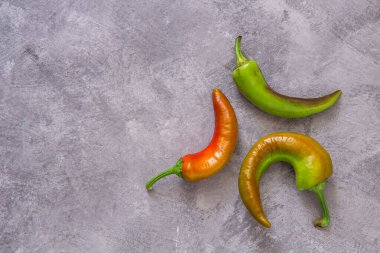 Gri arkaplanda üç yeşil ve kırmızı biber