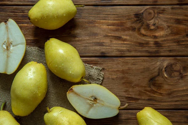 Yellow pears lie on a wooden background.