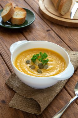 Kahverengi arka planda kızarmış ekmek ve balkabağı kremalı çorba.