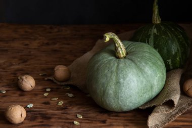 İki yeşil balkabağı koyu bir arka planda duruyor.