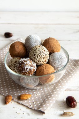 Fındıklı enerji topları ve beyaz arka planda cam bir kasede hurma.