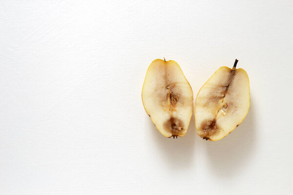 Two halves of a spoiled pear lie on a white background