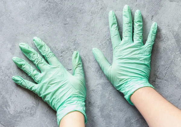 Hands in nitrile green gloves on a concrete surface