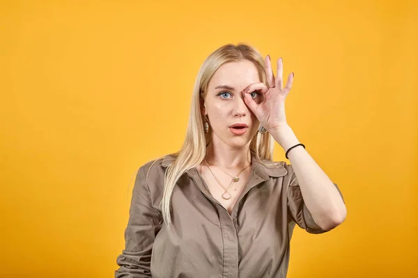 blonde girl in brown blouse over isolated orange background shows emotions