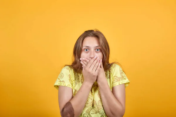 Chica morena en camiseta amarilla sobre fondo naranja aislado muestra emociones — Foto de Stock