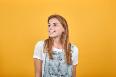 Beyaz tişört giyen genç kadın, turuncu arka plan üzerinde duygularını gösterir