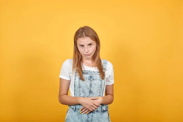Giovane donna che indossa t-shirt bianca, su sfondo arancione mostra emozioni — Foto Stock