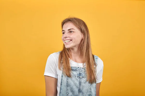 Mladá žena na bílém tričku, nad oranžovým pozadím vykazuje emoce — Stock fotografie