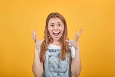 Beyaz tişört giyen genç kadın, turuncu arka plan üzerinde duygularını gösterir