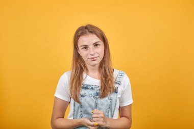 Beyaz tişört giyen genç kadın, turuncu arka plan üzerinde duygularını gösterir