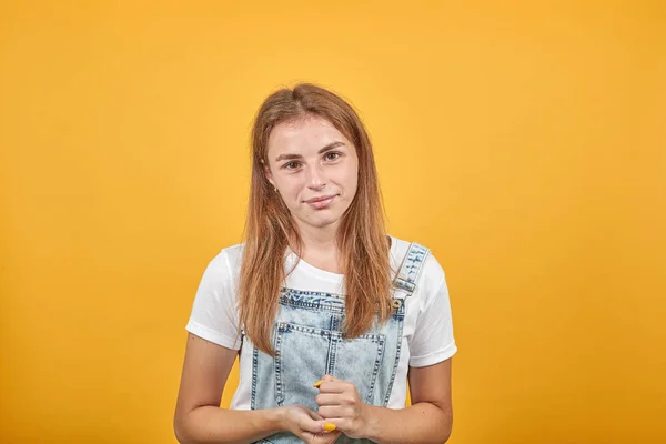 Beyaz tişört giyen genç kadın, turuncu arka plan üzerinde duygularını gösterir — Stok fotoğraf