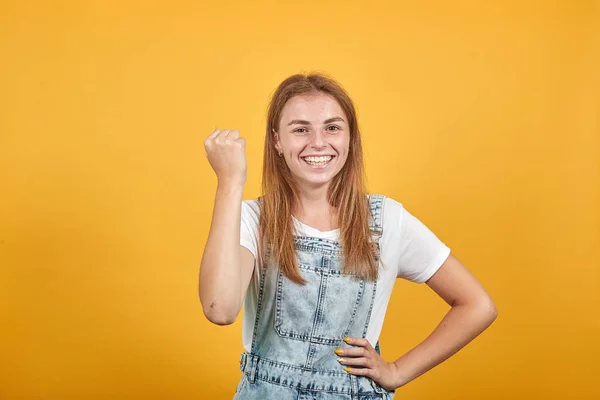 Молода жінка в білій футболці на помаранчевому фоні показує емоції — стокове фото