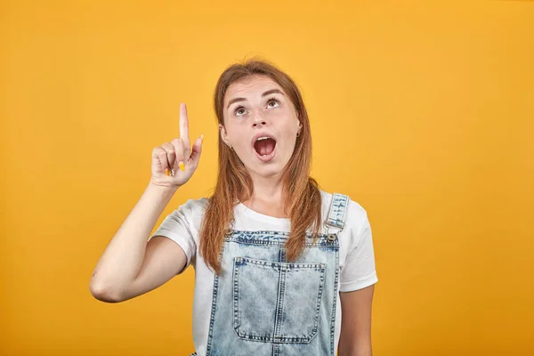 Ung kvinna klädd i vit t-shirt, över orange bakgrund visar känslor — Stockfoto