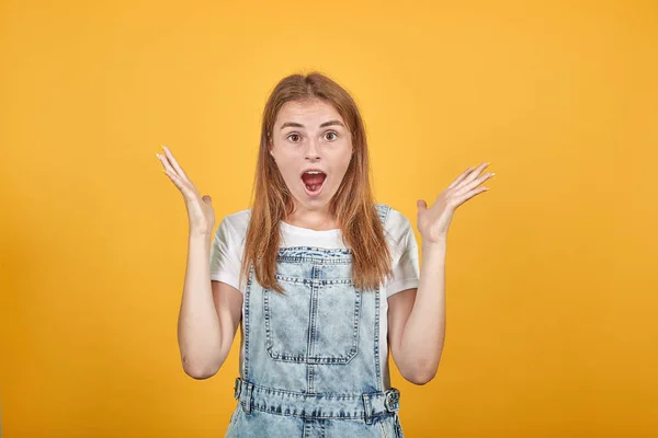 Ung kvinna klädd i vit t-shirt, över orange bakgrund visar känslor — Stockfoto