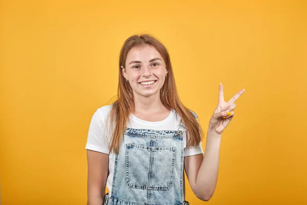 Beyaz tişört giyen genç kadın, turuncu arka plan üzerinde duygularını gösterir — Stok fotoğraf