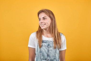 Beyaz tişört giyen genç kadın, turuncu arka plan üzerinde duygularını gösterir