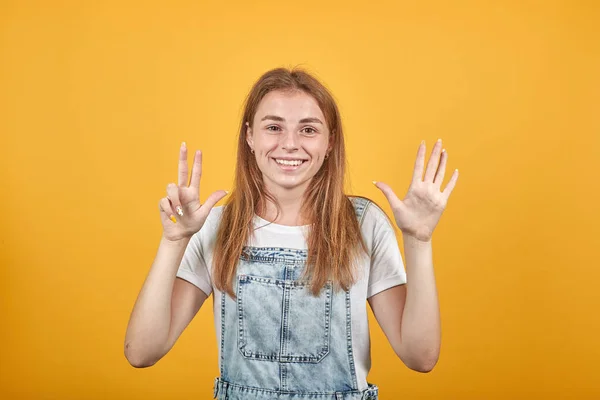 Mujer joven vistiendo camiseta blanca, sobre fondo naranja muestra emociones —  Fotos de Stock