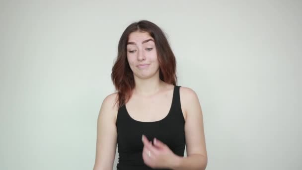 Beautiful girl in black tank top over isolated white background shows emotions — Stock Video