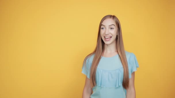 Дівчина брюнетка в синій футболці над ізольованим помаранчевим фоном показує емоції — стокове відео