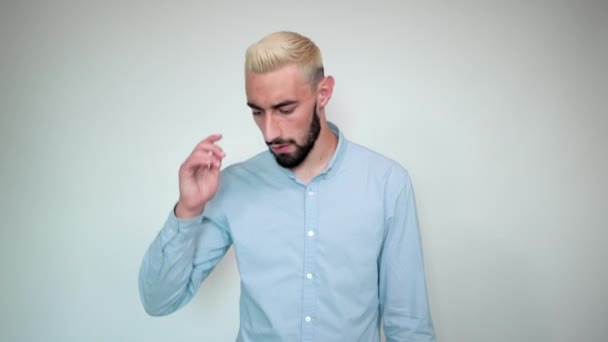 Hombre con cabello rubio, barba negra sobre fondo blanco aislado muestra emociones — Vídeos de Stock