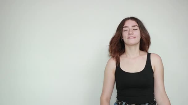 Belle fille en débardeur noir sur fond blanc isolé montre des émotions — Video