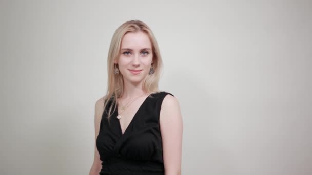 Blonde girl in a black dress over isolated white background shows emotions — Stock Video