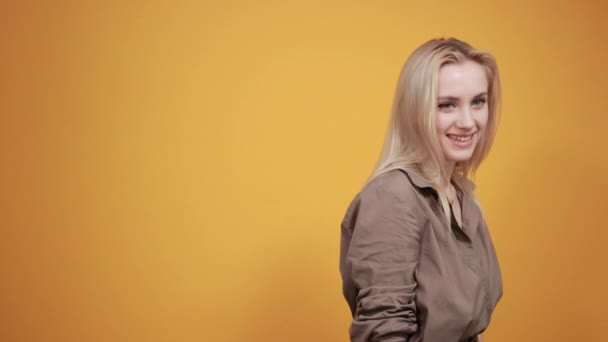 금발의 소녀 에 갈색 블라우스 위에 고립 된 오렌지 배경 쇼 감정 — 비디오