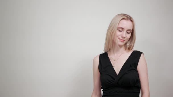 Blond dziewczyna w czarnej sukni na białym tle pokazuje emocje — Wideo stockowe