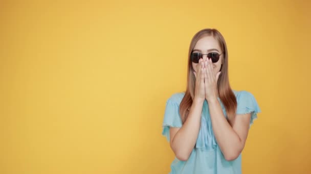 Girl brunette in blue t-shirt over isolated orange background shows emotions — Stock Video