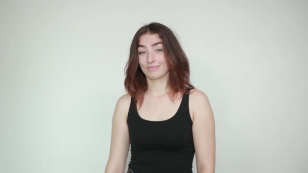 Mooi meisje in zwarte tank top over geïsoleerde witte achtergrond toont emoties — Stockvideo