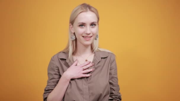 Blonde girl in brown blouse over isolated orange background shows emotions — Stock Video