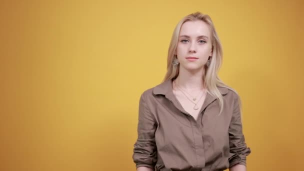 Blondes Mädchen in brauner Bluse über orangefarbenem Hintergrund zeigt Emotionen — Stockvideo