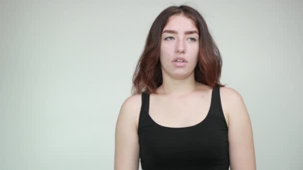Beautiful girl in black tank top over isolated white background shows emotions — Stock Video
