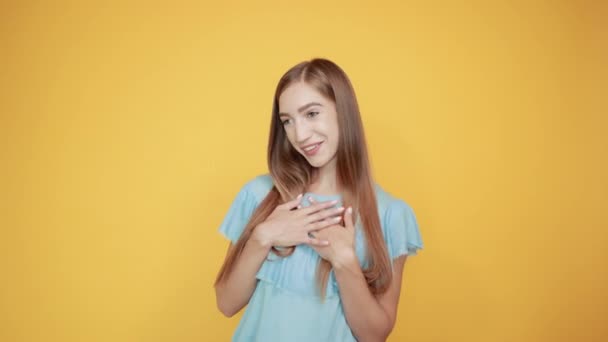 Дівчина брюнетка в синій футболці над ізольованим помаранчевим фоном показує емоції — стокове відео