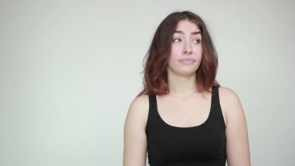 Beautiful girl in black tank top over isolated white background shows emotions — Stock Video
