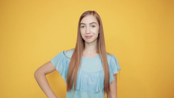 Girl brunette in blue t-shirt over isolated orange background shows emotions — Stock Video