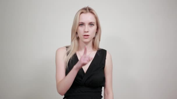 Rubia chica en un negro vestido sobre aislado blanco fondo muestra emociones — Vídeo de stock