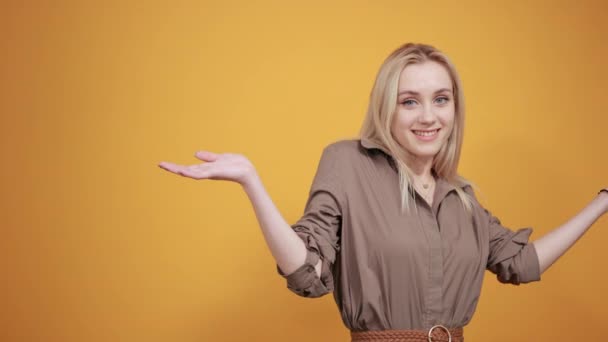 Blonde girl in brown blouse over isolated orange background shows emotions — Stock Video