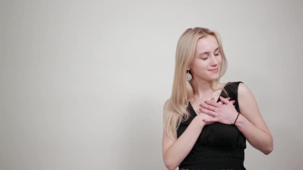 Blonde girl in a black dress over isolated white background shows emotions — Stock Video