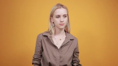 izole turuncu arka plan üzerinde kahverengi bluz sarışın kız duyguları gösterir